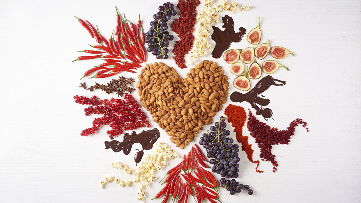 Heart-shaped almonds surrounded by fruits, spices, and chocolate