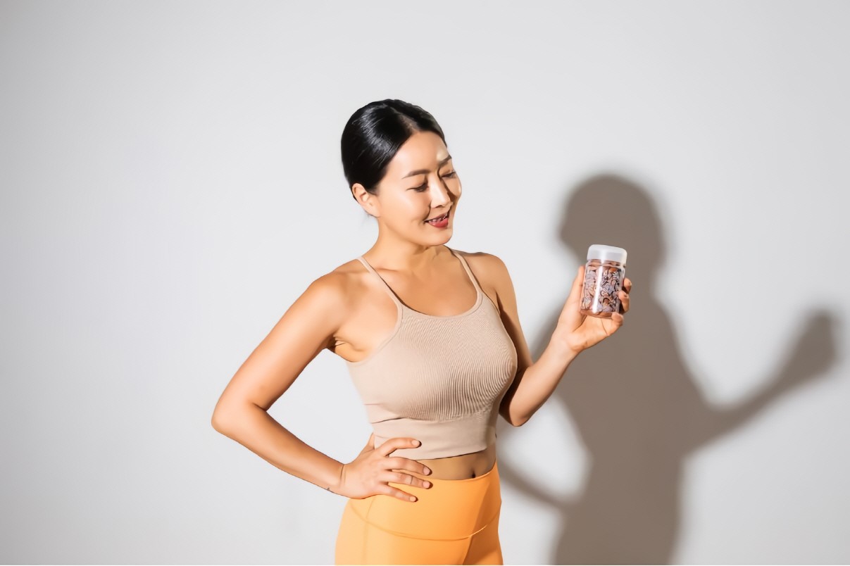 a woman with athletic clothing on holding almond bottle